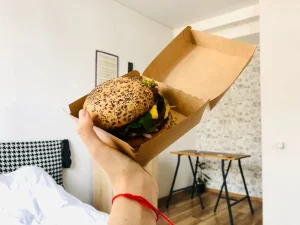 mana unei persoane tinand o cutie cu un buger d ela un fast food